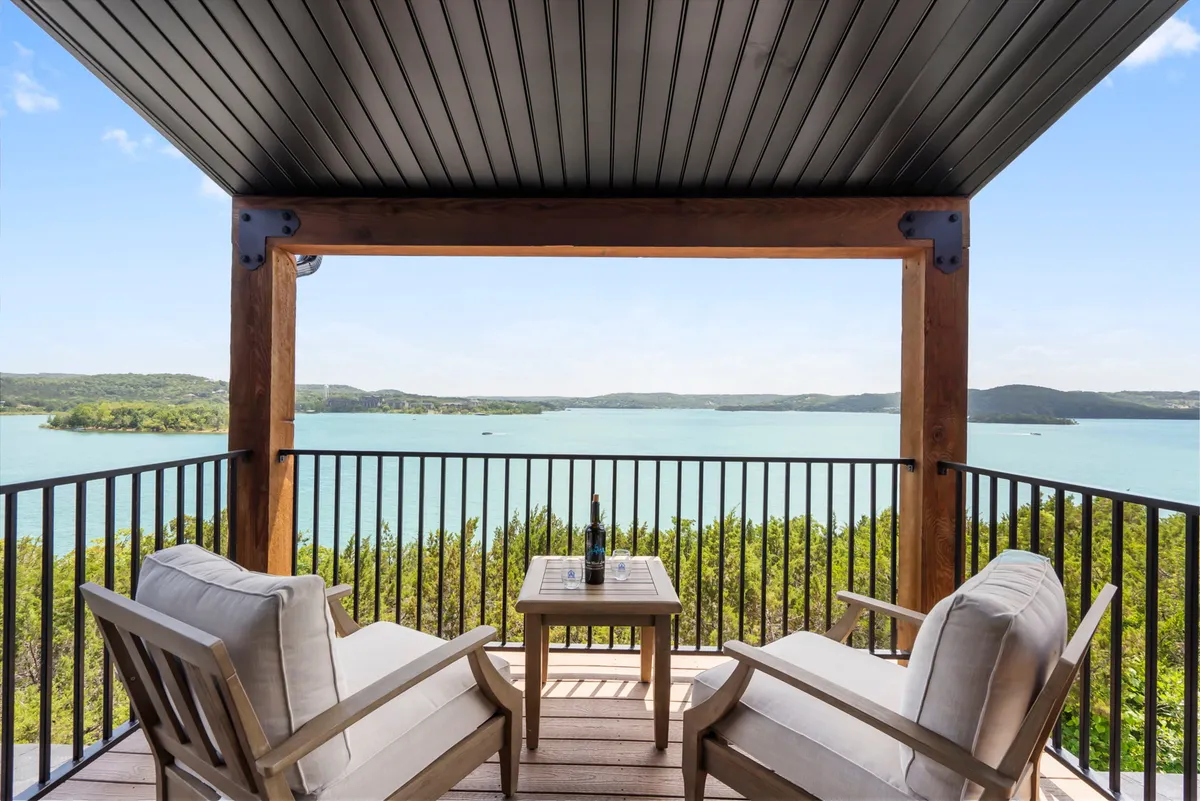 The image showcases a serene outdoor seating area overlooking a sparkling lake, with a small table perfectly positioned for relaxing, reading, or enjoying a drink while taking in the breathtaking views. The peaceful scene invites guests to unwind, watch sunsets, or gather with friends and family for memorable moments amidst natural beauty.