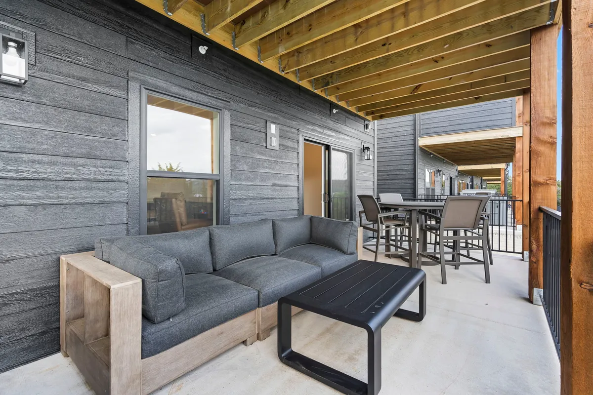 An outdoor seating area featuring dark wooden furniture and a black coffee table, arranged for socializing or casual dining. The setup is cozy and relaxed, making it an ideal spot for guests to unwind with their pets after a lakeside adventure.