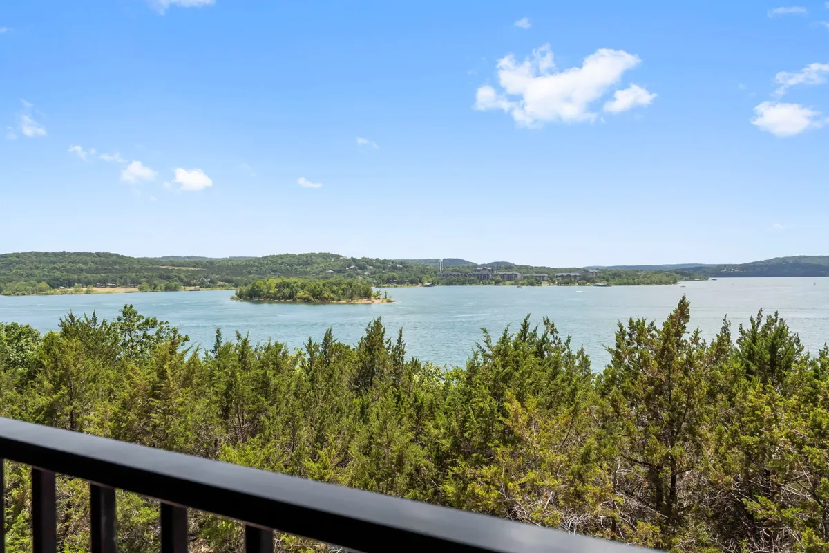 A breathtaking panoramic view of Table Rock Lake with a tranquil island, lush trees along the shoreline, and a serene sky above. The vantage point suggests opportunities for lake activities such as boating and fishing, and the natural setting is perfect for a lakeside picnic.