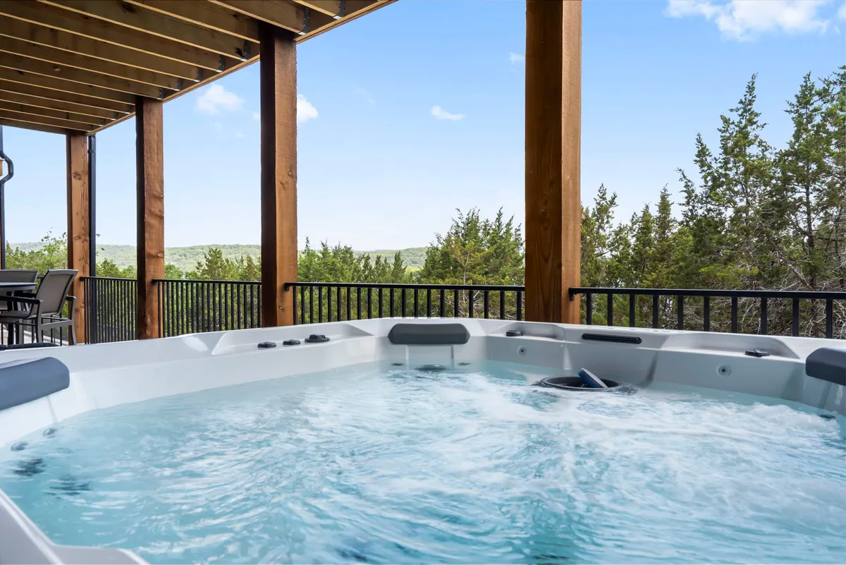 A tranquil outdoor hot tub nestled among wooden beams and surrounded by natural scenery. The setting is peaceful, ideal for relaxing while gazing at the stars or taking in the morning light and nature views.